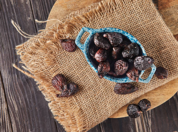 Dried mission figs in glass bowl on burlap and wooden background. Flat lay