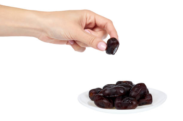 Dried dates with hand on plate isolated on white background.