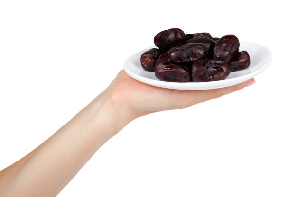 Dried dates with hand on plate isolated on white background.