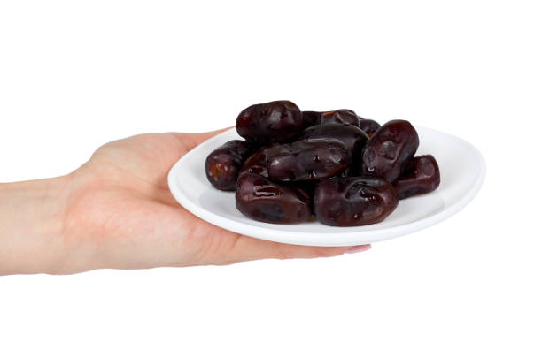 Dried dates with hand on plate isolated on white background.